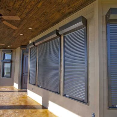 Bronze motorized roll-down shutters partly lowered over patio windows and a doorway